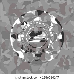 cheeseburger icon inside grey camouflage emblem