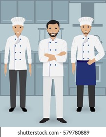 Chef and two cook in uniform standing together on a kitchen background. Cooking people characters. Flat vector illustration.