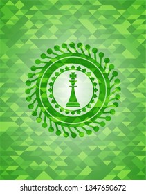 chess king icon inside green emblem with triangle mosaic background