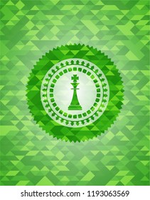 chess king icon inside realistic green emblem. Mosaic background