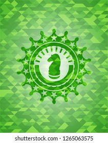 chess knight icon inside green emblem with triangle mosaic background