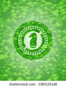 chess knight icon inside green emblem with triangle mosaic background