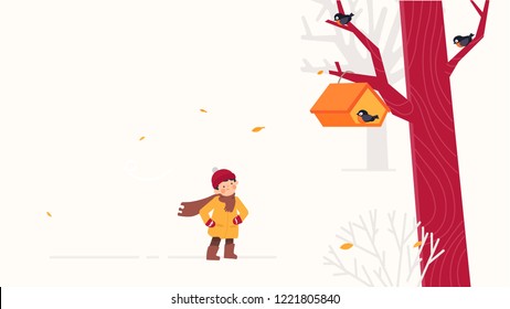 Child feeds birds in a birdfeeder