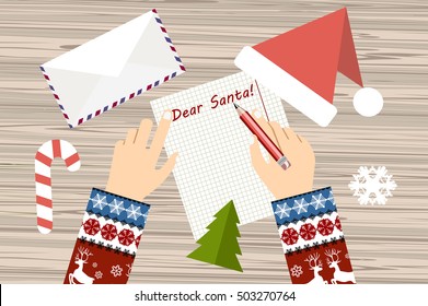 Child Hand with pen Writing letter to santa claus. wooden desk with candycane, envelope