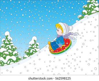 Child on a snow tube sliding down the snow hill