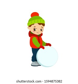 A child sculpts a snowman. The boy is rolling a snowball. Winter vacation.