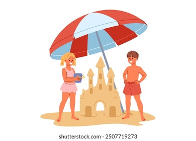 Children build sand castle on beach, standing with umbrella to protect them from sun. Little positive boy and girl play together on beach during summer trip to sea or ocean with parents