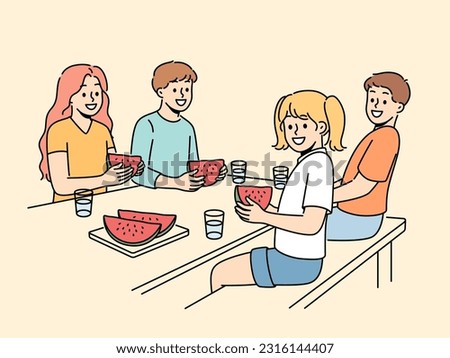 Children eat watermelon sitting at table and enjoying sweet refreshing dessert on hot summer day. Childrens picnic for boys and girls with delicious watermelon containing healthy vitamins