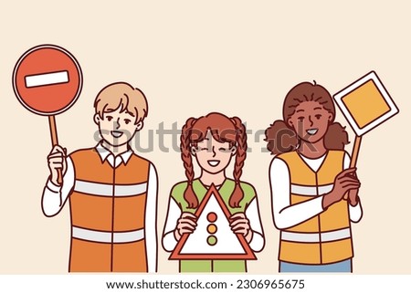 Children learning rules of road wear reflective vests and display traffic sign to help pedestrians and drivers. Schoolchildren play traffic inspectors to learn rules of moving around city