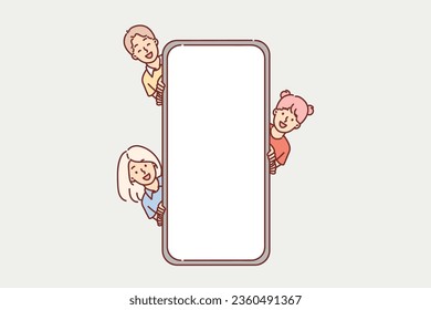 Children near giant phone with empty screen, to demonstrate kids application or website for schoolchildren. Happy elementary school boys and girls with phone mock up for offer from kids online store