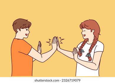 Children play hand-clapping laughing and enjoying teenage friendship and happy childhood. Boy and girl play hand-clapping after school for concept of children socialization through active games