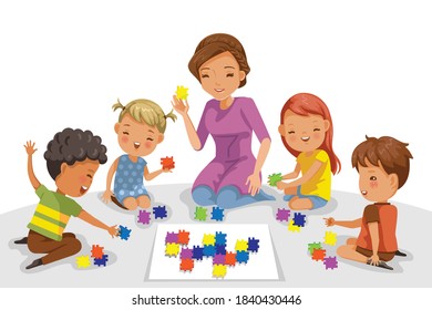 Children playing with a teacher in kindergarten. Kids are playing puzzle games on the floor together. International boys and girls group. Mentor and child activities in the nursery.