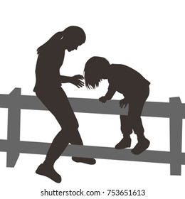 Children silhouettes climbing a wooden fence