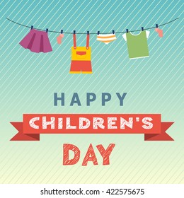 Children's Day concept. On a blue background baby clothes
 and red ribbon with the inscription Children's Day.
