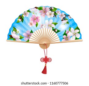 Chinese fan with a pattern of pink spring sakura flowers on blue sky. On the handle of the folding fan red wishful knot. Isolated on white background.