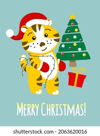 A Chinese tiger, a funny character in a Santa Claus hat next to the Christmas tree. Christmas card. The symbol of 2022.
