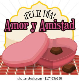 Chocolate box with heart shape almost empty, with few chocolates over picnic tablecloth in the celebration for Love and Friendship Day (written in Spanish).
