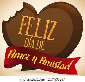 Chocolate heart half bitten with greeting message in red ribbon to celebrate Day of Love and Friendship (written in Spanish).