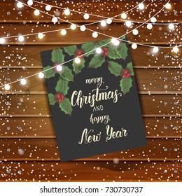Christmas background with greeting card and garlands on wooden board. Hand made quote "Merry Christmas and Happy New Year". Festive background. Lettering, sketch. Banner, poster, brochure.