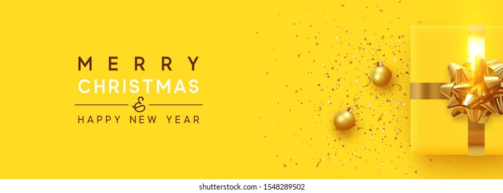 Christmas background. Realistic yellow gift boxes, with shiny golden confetti, Xmas balls, decorative baubles. Flat lay, top view. Horizontal Festive New Year poster, greeting cards, headers, website.