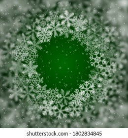 Weihnachtshintergrund von Schneeflocken verschiedener Form, unscharf und transparent, in einem Kreis auf grünem Hintergrund angeordnet