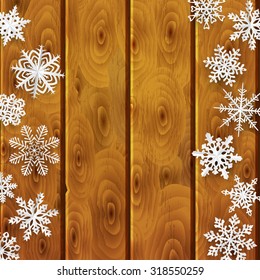 Christmas background with white paper snowflakes on brown wooden planks