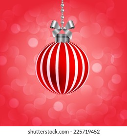 Christmas ball hanging on chain with tied ribbon on sparkling background.