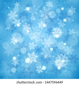 Christmas blurred background of complex defocused big and small falling snowflakes in light blue colors with bokeh effect