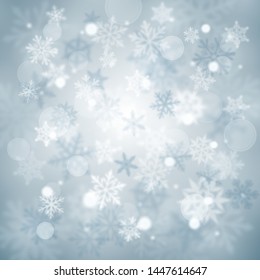 Christmas blurred background of complex defocused big and small falling snowflakes in light blue colors with bokeh effect