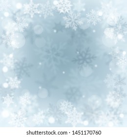 Christmas blurred background of complex defocused big and small falling snowflakes in light blue colors with bokeh effect
