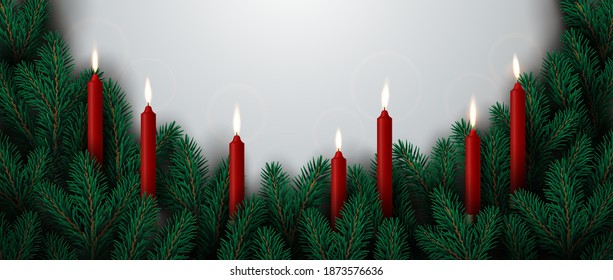 Christmas border made of evergreen branches decorated with burning candles