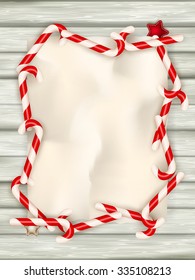 Christmas border with a red and white candie canes around blank paper as a copy space on wooden planks, wooden table background, New year theme. EPS 10 vector file included