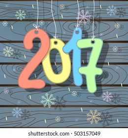 Christmas card 2017 New Year with hanging bright colored figures and falling snowflakes on gray blue wooden background.