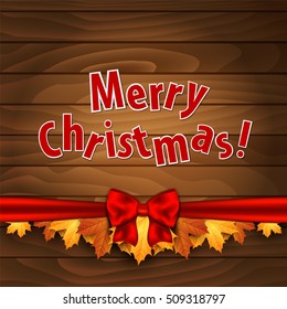 Christmas card. Border of autumn maples leaves decorated with a red bow on a wooden background.