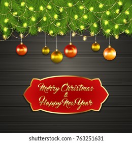 Christmas card with Cristmas fir tree branches on top, glowing garland and Christmas tree balls on black wooden board with greeting text Merry Chrismas and Happy New Year on red label with gold frame