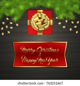 Christmas card with Cristmas fir tree branches, red square gift box with gold ribbon bow, garland on black wooden board. Greeting text Merry Chrismas and Happy New Year on red label with gold frame