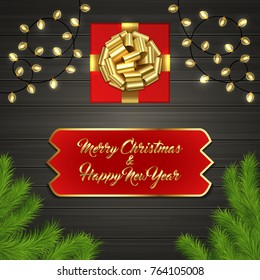 Christmas card with Cristmas fir tree branches, red square gift box with gold ribbon bow, garland on black wooden board. Greeting text Merry Chrismas and Happy New Year on red label with gold frame