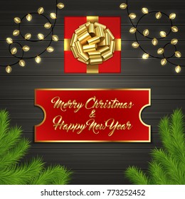 Christmas card with Cristmas fir tree branches, red square gift box with gold ribbon bow, garland on black wooden board. Greeting text Merry Chrismas and Happy New Year on red label with gold frame