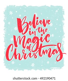 Christmas card design. Believe in the magic of Christmas. Inspirational xmas quote. Red brush calligraphy text on blue background with snowflakes