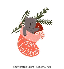 Christmas card. A gift sock with a teddy bear, candy and a gift hanging on a spruce branch. Lettering MERRY CHRISTMAS.