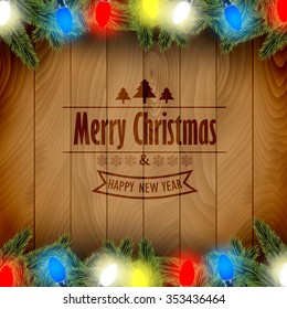 Christmas card with pine tree branches and color Christmas lights on a wooden board.