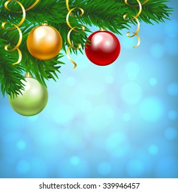 Christmas card with red, yellow and green balls on fir tree branch and blue shiny background
