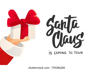 Christmas card. Santa Claus is coming text. Cartoon flat illustration. Hand holding present with bow. Gift box with red ribbon. Great for Christmas and New Year posters, gift tags, labels, banners.
