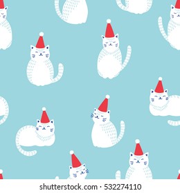 Christmas cats seamless pattern. White cute cats in red Christmas hats on blue background