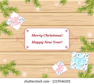 Christmas composition. Christmas gift, falling snowflakes and fir branches on wooden background. Flat lay, top view, copy space