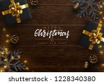Christmas composition on wooden background. Xmas decoration design, box gift, snowflake color black, gold light garland, pine cone. Brown realistic wood texture. Flat lay, top view.