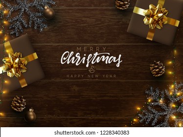 Christmas composition on wooden background. Xmas decoration design, box gift, snowflake color black, gold light garland, pine cone. Brown realistic wood texture. Flat lay, top view.