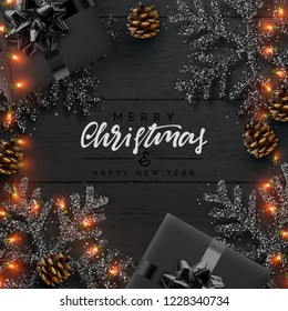 Christmas composition on wooden background. Xmas decoration design, box gift, snowflake color black, gold light garland, pine cone.  Wood texture. Flat lay, top view.