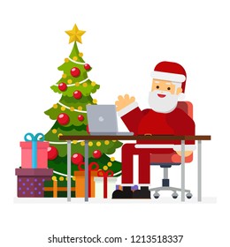 Christmas concept,Modern Santa Claus sitting at Desk and working on his laptop. Christmas tree with gift boxes