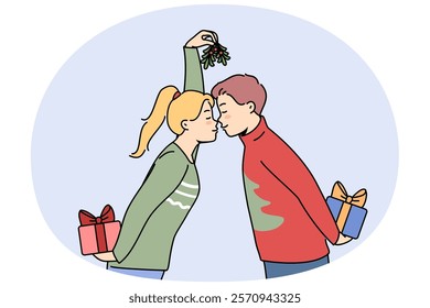 Christmas couple with gift boxes kisses and holds fir cones in hands, preparing to exchange new year presents. Husband and wife in christmas sweaters celebrate winter holidays together